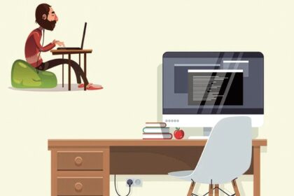 Cartoon of a bearded person sitting on a green bean bag and typing on a laptop at a desk with a desktop computer, books, and an apple nearby.