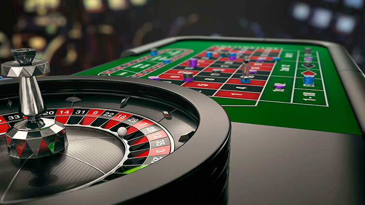 Roulette wheel in the foreground with a green casino betting table and chips in the background.