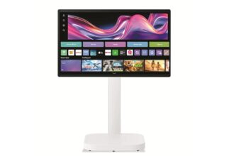 Widescreen monitor on a white stand showing a colorful home-screen interface with app tiles and icons.