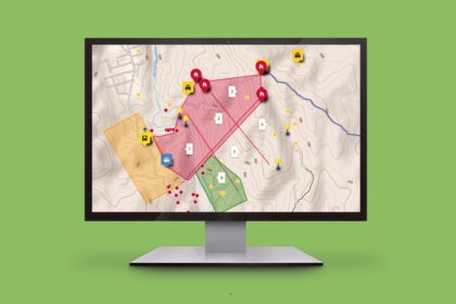 Monitor displaying a topographic map with colored zones, numbered plots, and warning icons for incidents on screen.