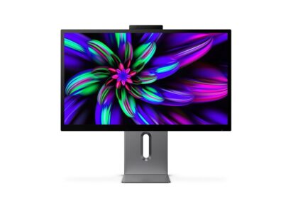 Slim computer monitor on a metal stand displaying a vibrant abstract wallpaper with neon greens, purples, and pinks. Center cutout in the stand is visible.