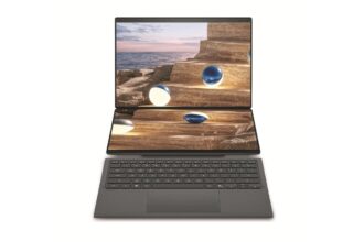 Dual-screen laptop with a coastal rock staircase image displayed across both open screens and a dark gray keyboard below.