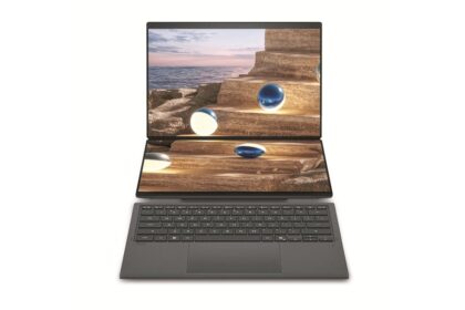 Dual-screen laptop with a coastal rock staircase image displayed across both open screens and a dark gray keyboard below.