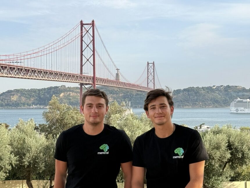 Two men in black shirts with a green brain logo pose in front of a red suspension bridge over water, with trees and a cruise ship in the background.