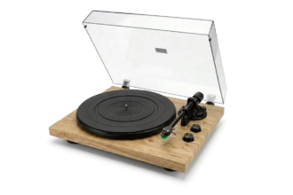 Wooden-turntable setup with a black circular platter, transparent lid raised, and the tonearm resting on the right side of the base with control knobs nearby.
