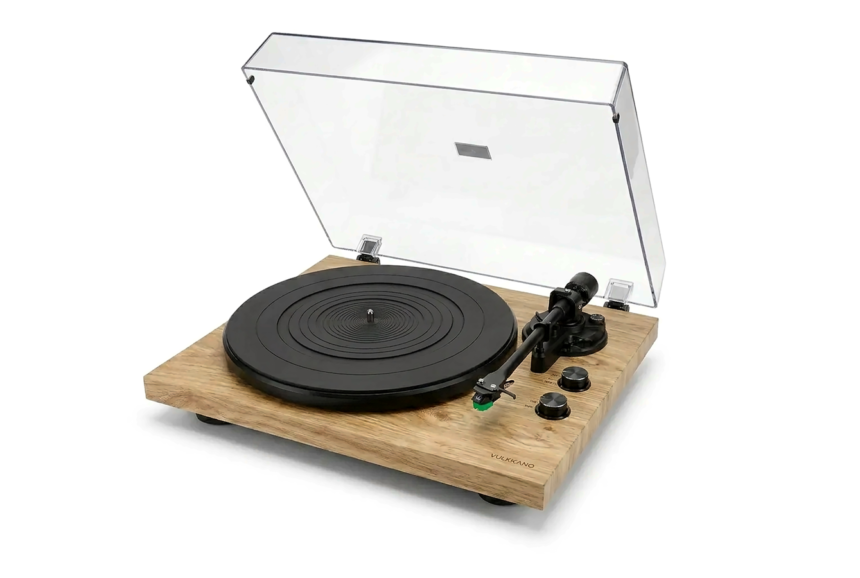 Wooden-turntable setup with a black circular platter, transparent lid raised, and the tonearm resting on the right side of the base with control knobs nearby.