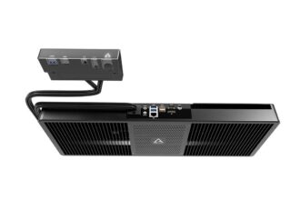 Black mini PC with a large ventilated front, connected to a small external I/O box via two cables.