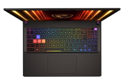 Top-down view of a black gaming laptop with a rainbow RGB keyboard lighting up the keys and a glowing screen edge above the keyboard