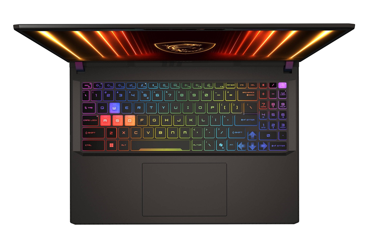 Top-down view of a black gaming laptop with a rainbow RGB keyboard lighting up the keys and a glowing screen edge above the keyboard