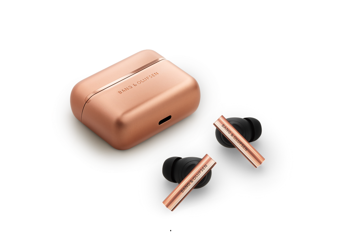 Rose-gold wireless earbuds with a matching rose-gold charging case; brand Bang & Olufsen visible on both pieces.