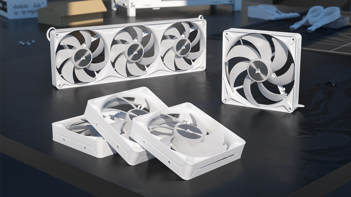 Set of white computer case fans of varying sizes arranged on a dark desk surface