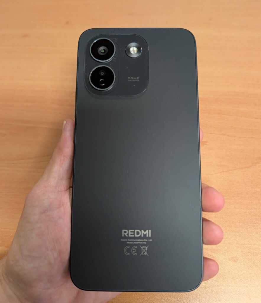 Back of a dark Redmi smartphone showing a square camera module with two large lenses and one smaller sensor; the text 50MP AI Camera is visible near the module and REDMI branding appears at the bottom.