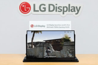 LG Display logo on the wall above a laptop showing a first-person shooter game on screen.