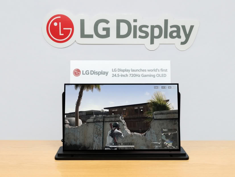 LG Display logo on the wall above a laptop showing a first-person shooter game on screen.