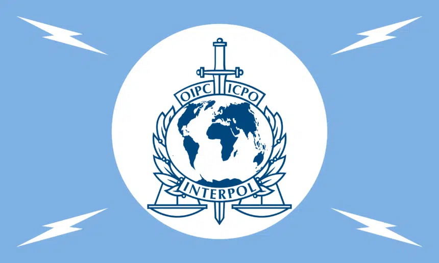 Interpol emblem featuring globe, sword, and scales on a white circle against a blue background.