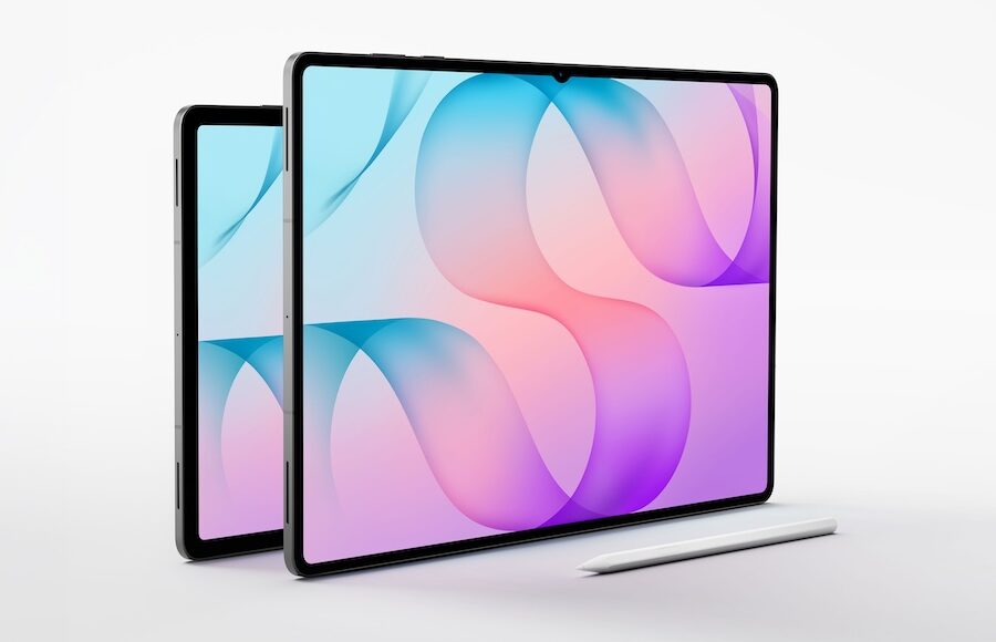 Two tablets with black frames leaning on a white surface, a white stylus resting in front, screens showing blue–pink abstract wallpaper.