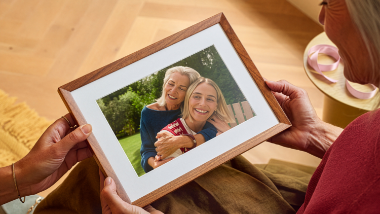 alexaphotoframe-inline-amazonnews-ck102526 | PCGuia Framed photo of two smiling women hugging outdoors, being held by a person.